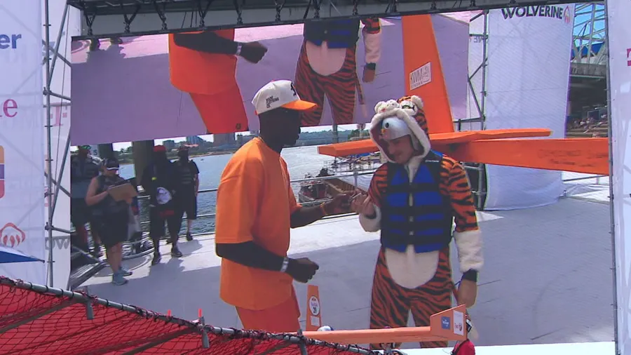 A team member in a tiger costume posing with Chad 'Ochocinco' Johnson by the glider.