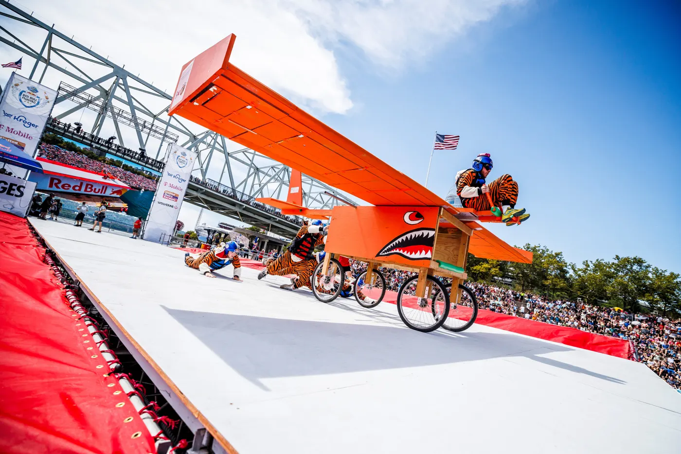 Our orange, tiger-striped glider rolling off the Flugtag flight deck with the pilot on top.
