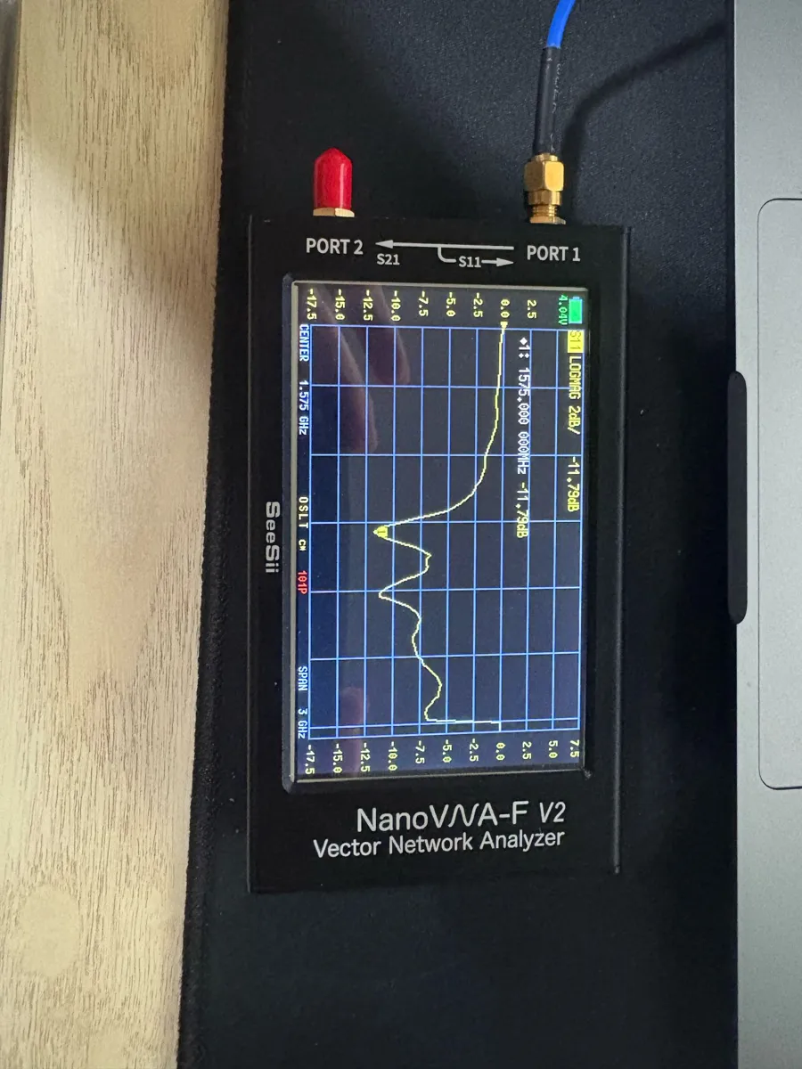 Handheld vector network analyzer screen showing an S11 trace with a dip.