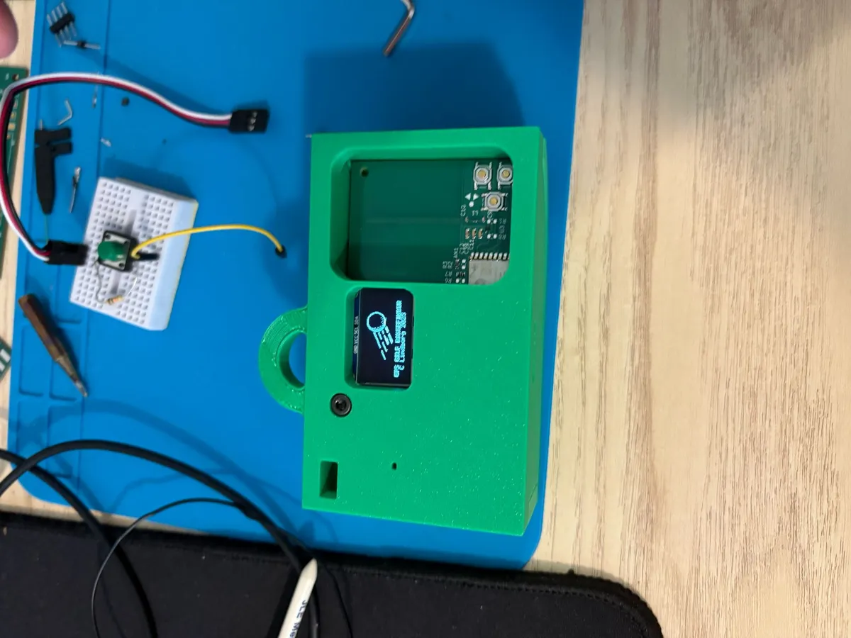 Green 3D-printed enclosure next to a range finder board with an OLED screen.