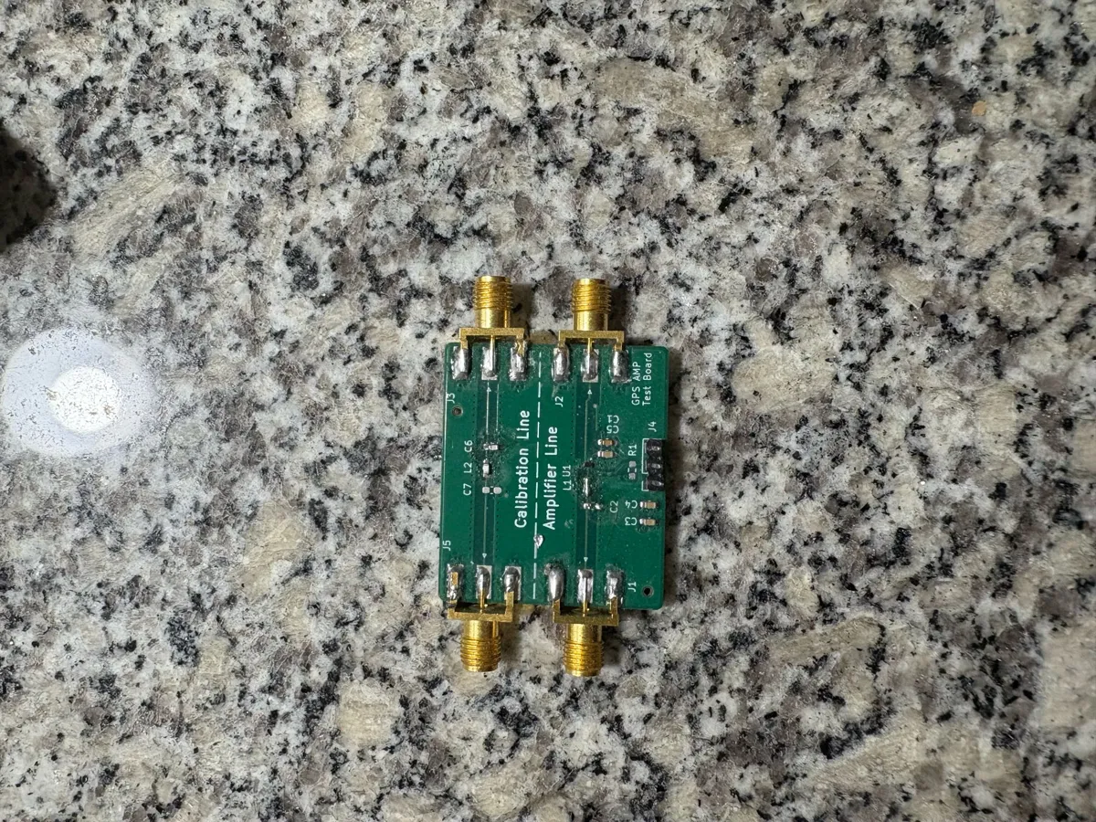 Small green matching-network test board with SMA connectors on a granite surface.