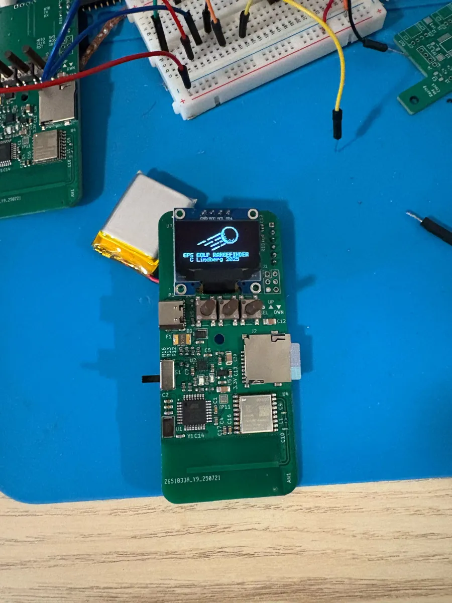 Rev 2 PCB with OLED screen, three buttons, microSD slot and USB-C port, next to a small LiPo battery.